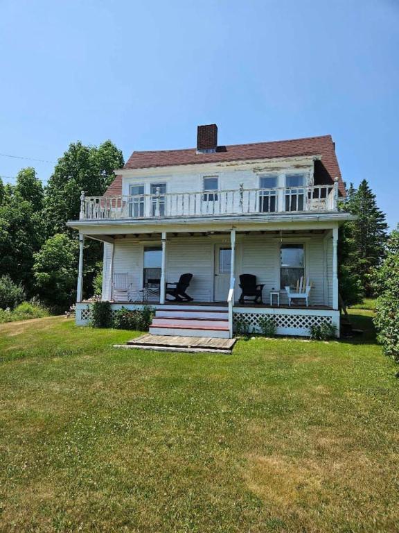 a white house with a porch with two chairs on it at Perry Shore Road Cottage in Perry