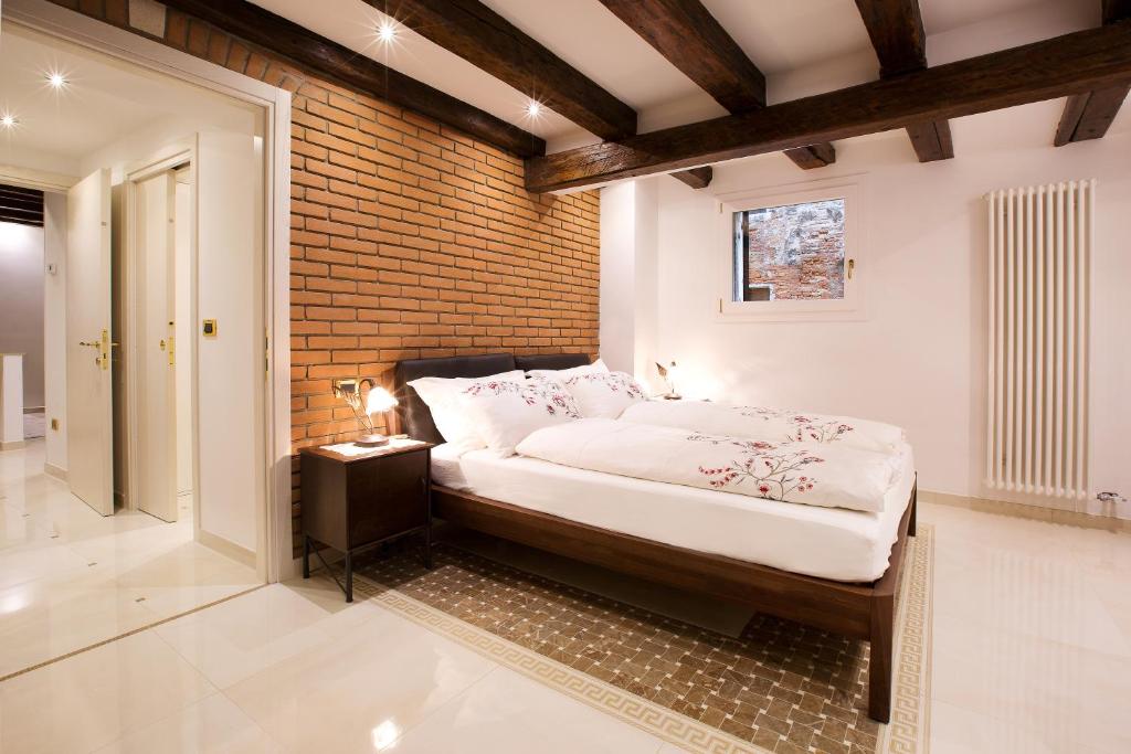 um quarto com uma cama e uma parede de tijolos em Moretta Apartment em Veneza