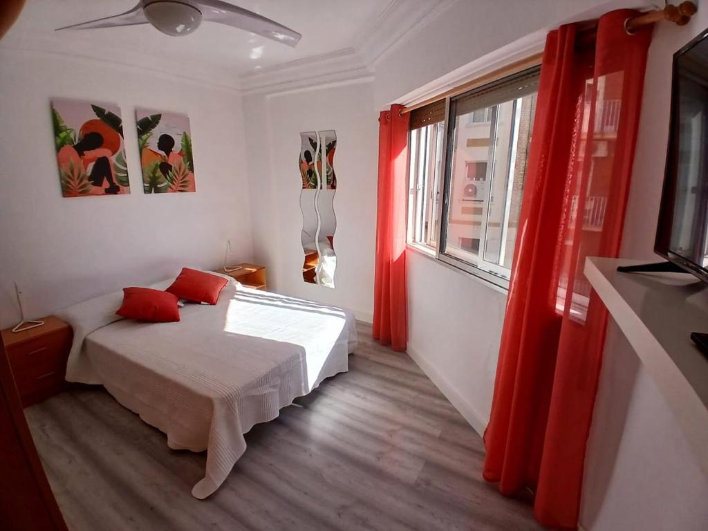 a bedroom with a bed and a window with red curtains at Piso recien reformado in Zaragoza