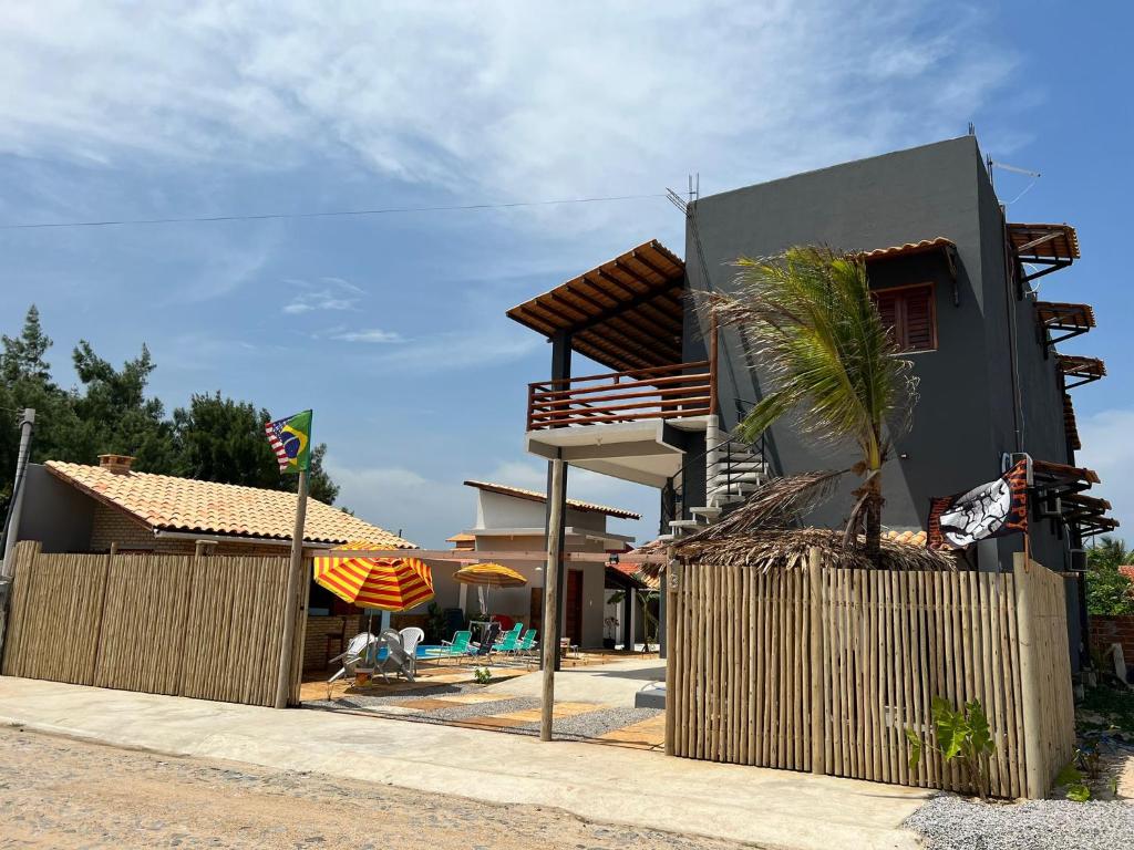 a house with a palm tree next to a fence at Pousada Califa Taíba in São Gonçalo do Amarante