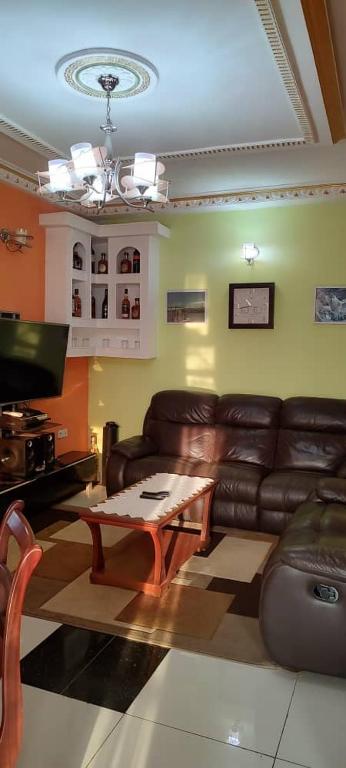 a living room with a leather couch and a coffee table at Olympus House Meublé in Yaoundé