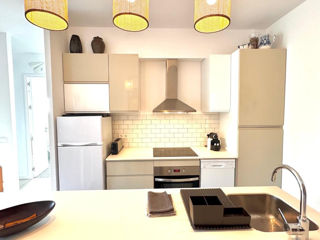 a kitchen with white cabinets and a sink at Appartement NoBe Es Pujols proche plage, vue mer in Es Pujols
