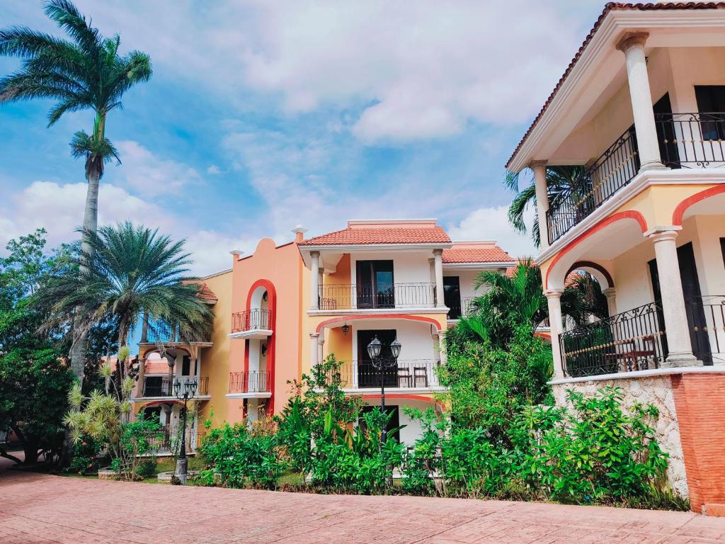 a yellow building with palm trees in front of it at Ecotel Quinta Regia in Valladolid