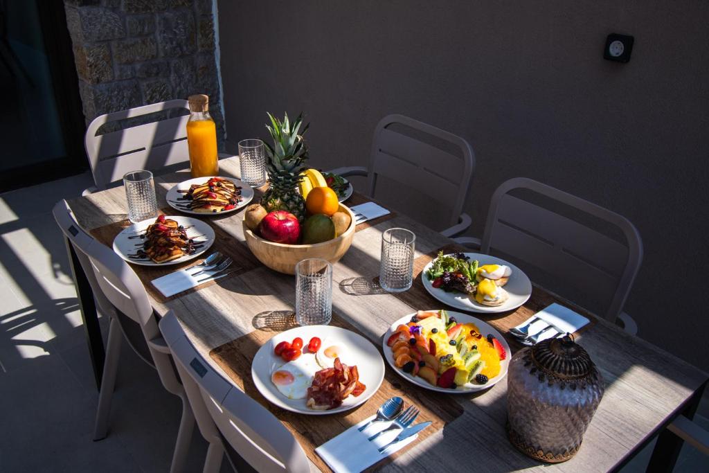 a wooden table with plates of food on it at Nestor Luxury Villas in Romanu
