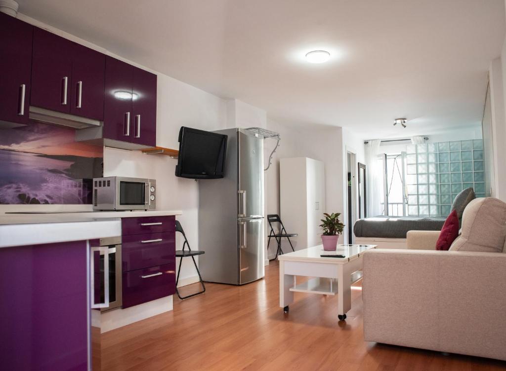 a kitchen and living room with purple cabinets and a couch at Apartamento Greco in Ronda
