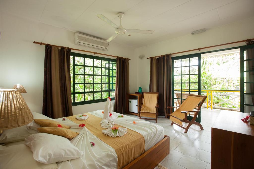 a bedroom with a large bed in a room with windows at Pension Michel in La Digue