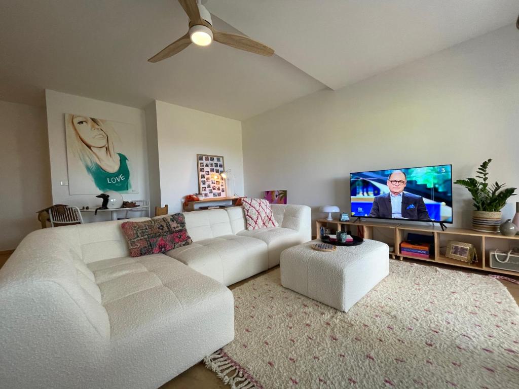 Il comprend un salon doté d'un canapé blanc et d'une télévision à écran plat. dans l'établissement Appartement Marinella route des Sanguinaires Corse, à Ajaccio