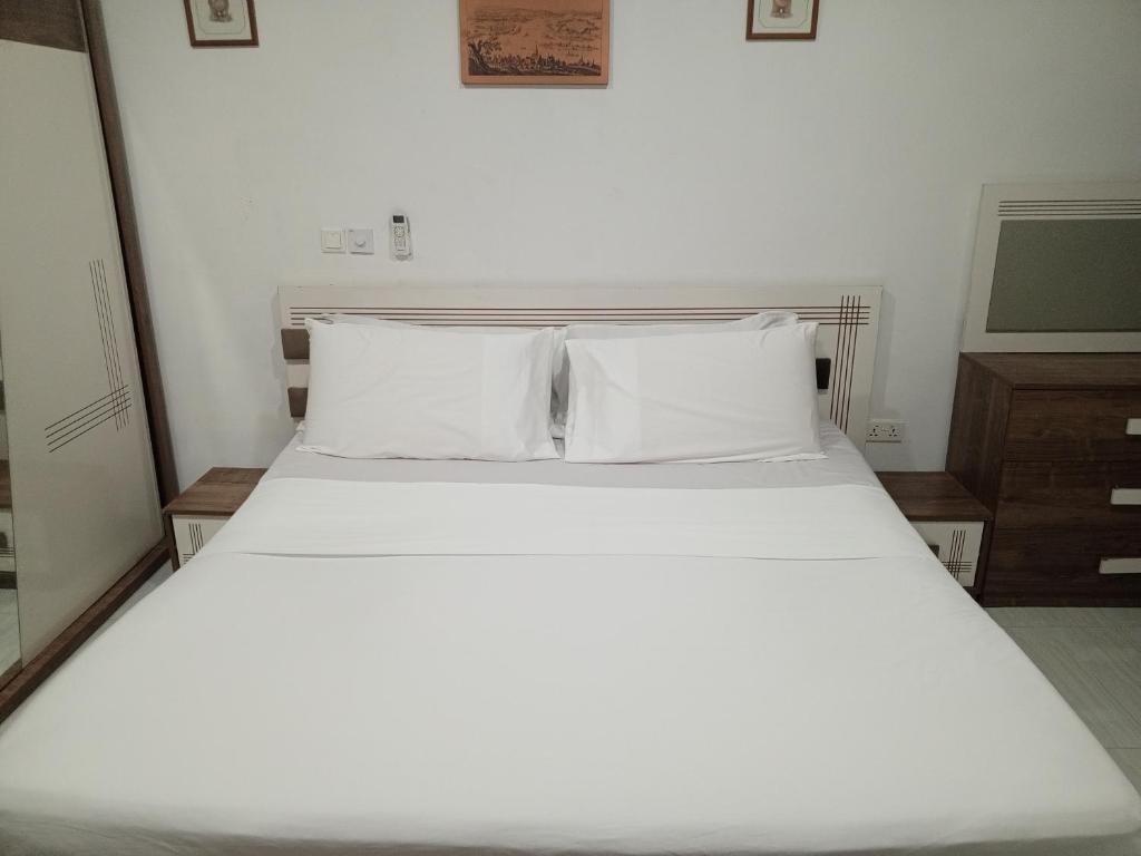 a bed with white sheets and pillows in a room at Holiday Home in Takoradi