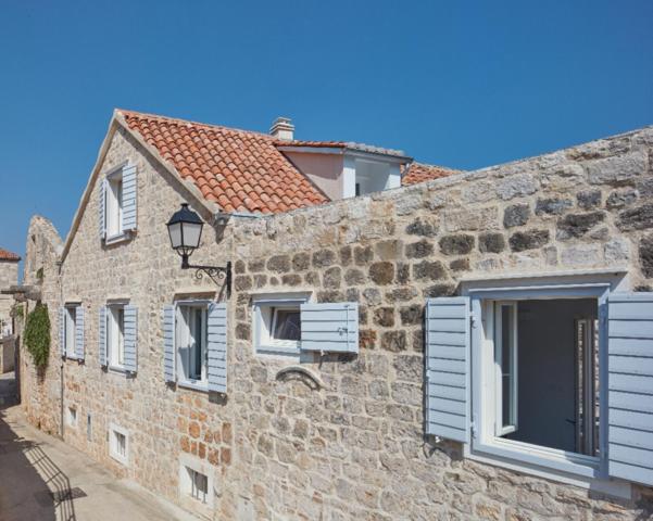 a stone building with white windows and a street at Orange Tree House in Vis