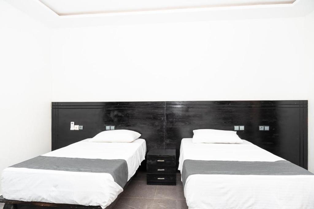 two beds in a room with white walls at Airport INN Hotel in Lomé