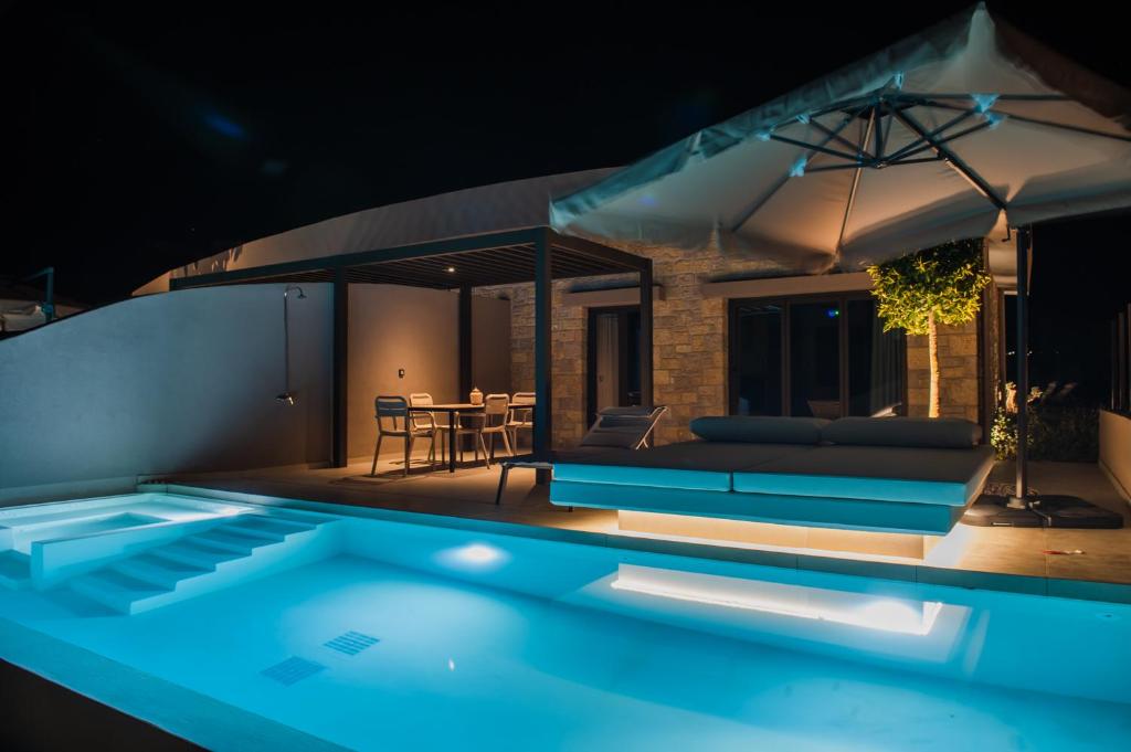 a swimming pool in front of a house at night at Nestor Luxury Villas in Romanu