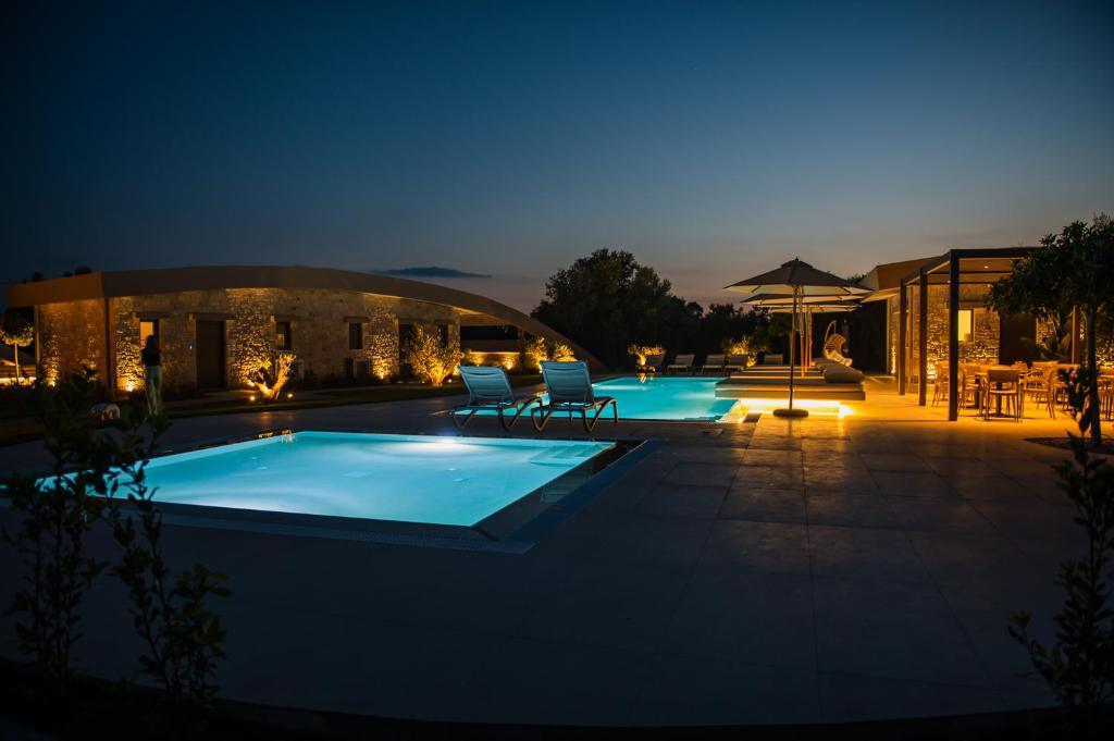 a pool at night with two chairs and an umbrella at Nestor Luxury Villas in Romanu