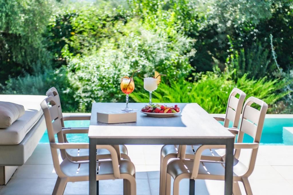 a table with a bowl of fruit and two glasses of wine at Nestor Luxury Villas in Romanu