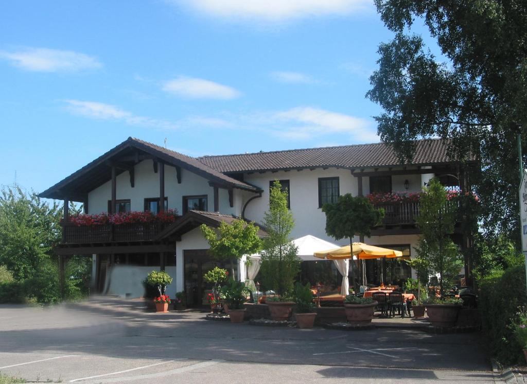 ein großes weißes Gebäude mit Tischen und Sonnenschirmen in der Unterkunft Restaurant Landgasthof Zum Wiesengrund in Newel