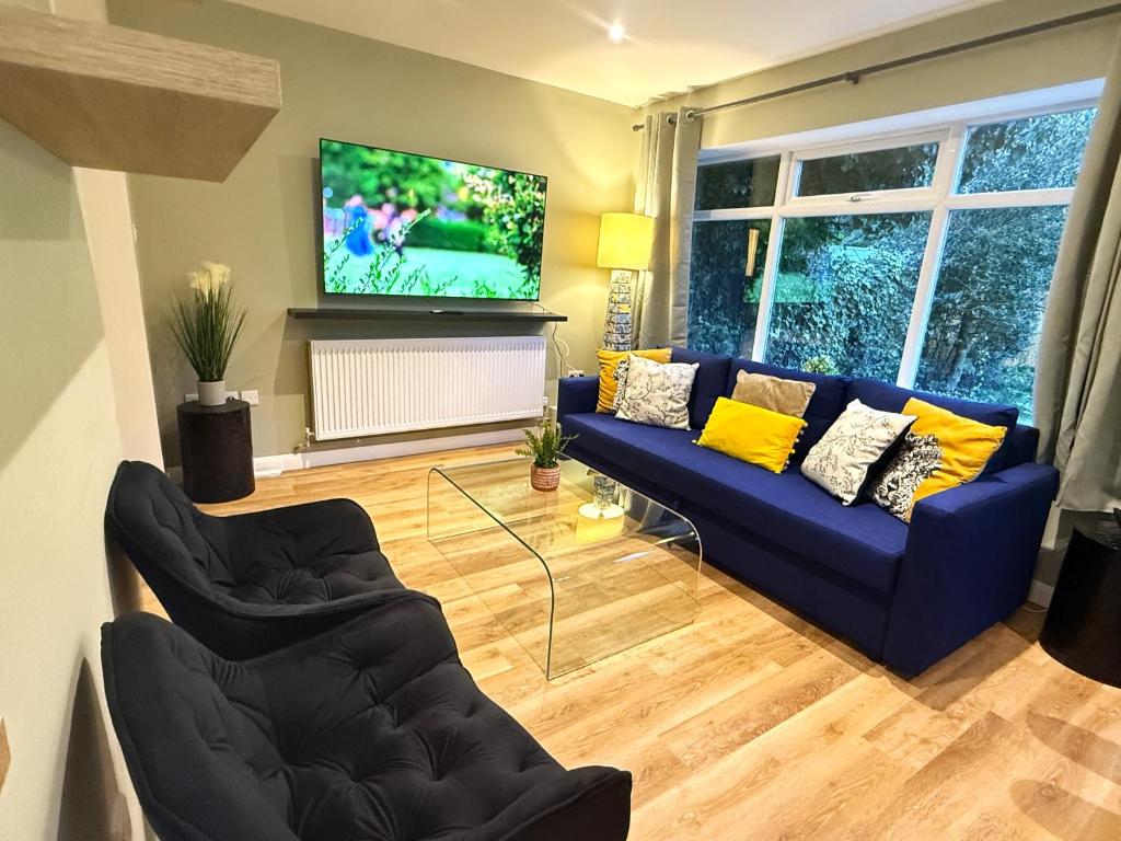 a living room with a blue couch and a tv at Bicester villa, 5Bedroom, Parking, WiFi, Garden in Bicester