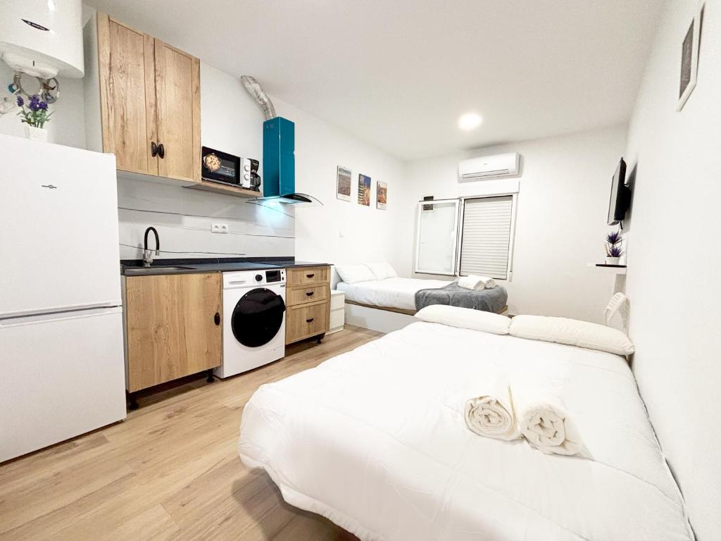 a white kitchen with a bed and a refrigerator at Nuevo, luminoso y céntrico in Madrid