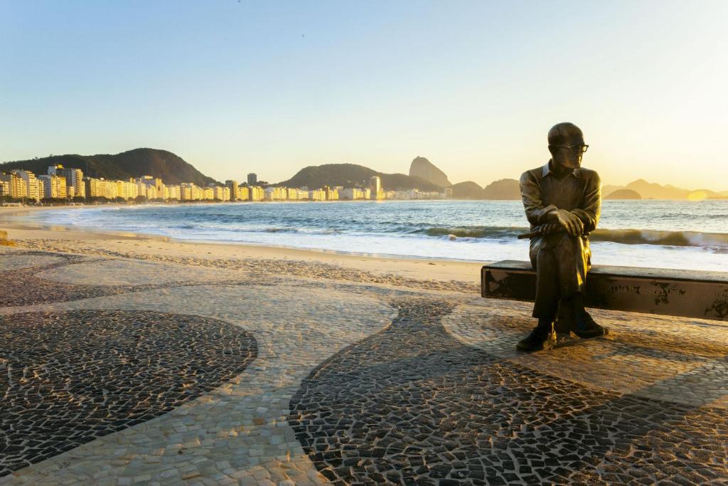 a man sitting on a bench on the beach at Windsor Martinique Copacabana in Rio de Janeiro