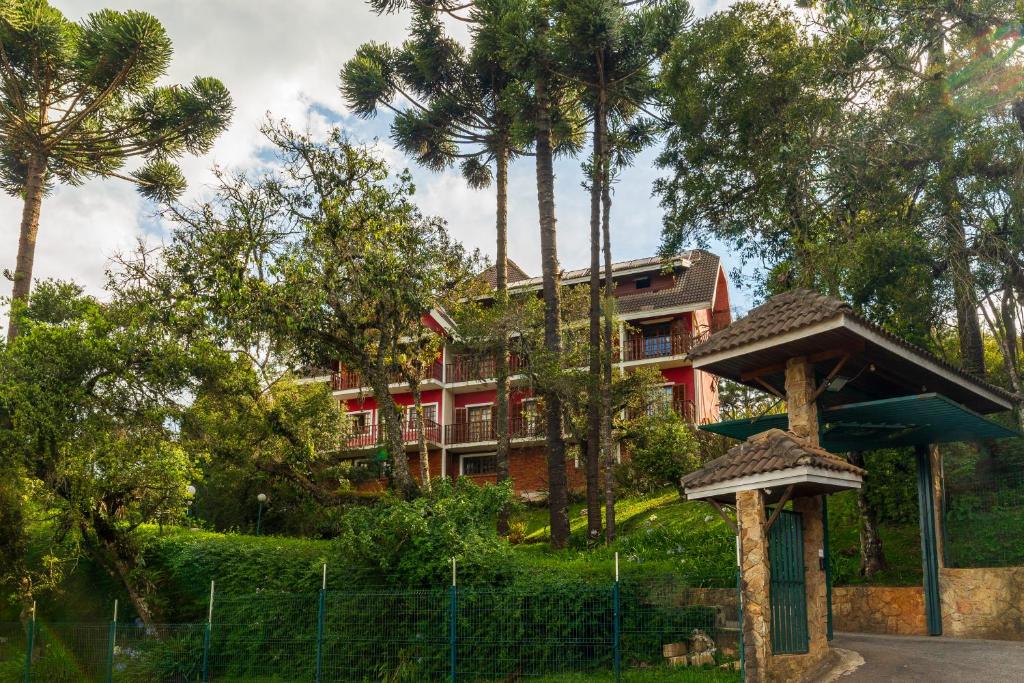 uma casa vermelha com palmeiras em frente em Pousada Serra do Jordão by Concavus em Campos de Jordão