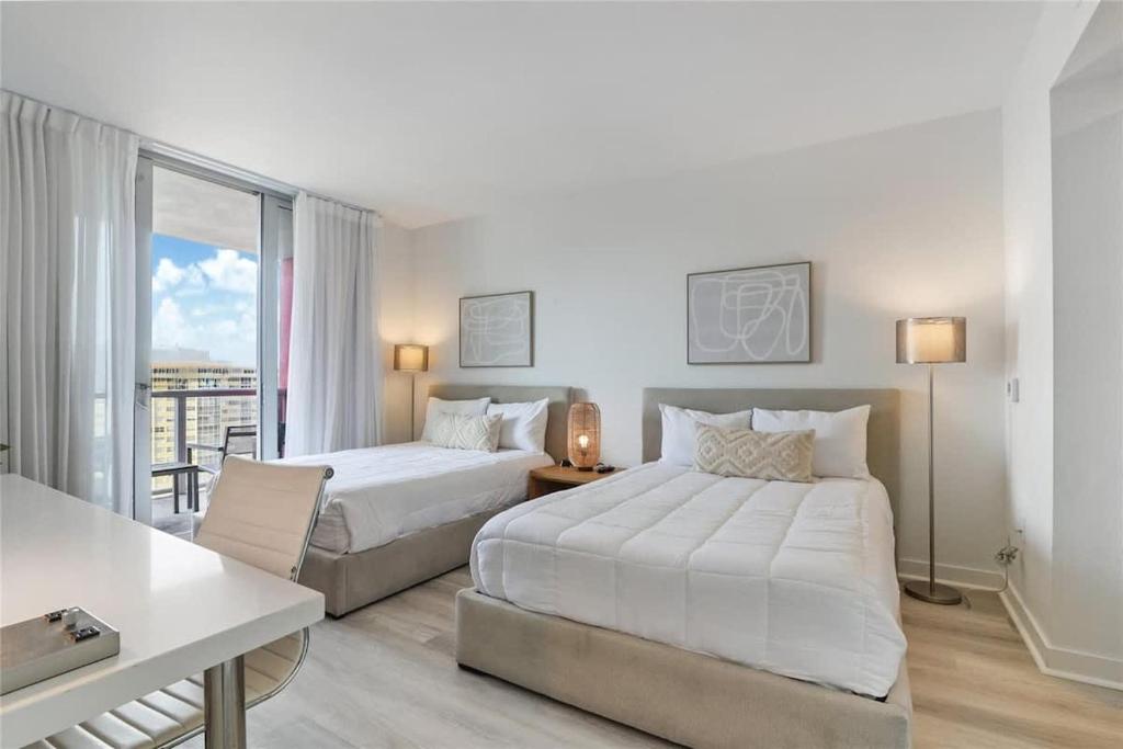 a hotel room with two beds and a table at Amazing Studio with Balcony & Pool in Hallandale Beach