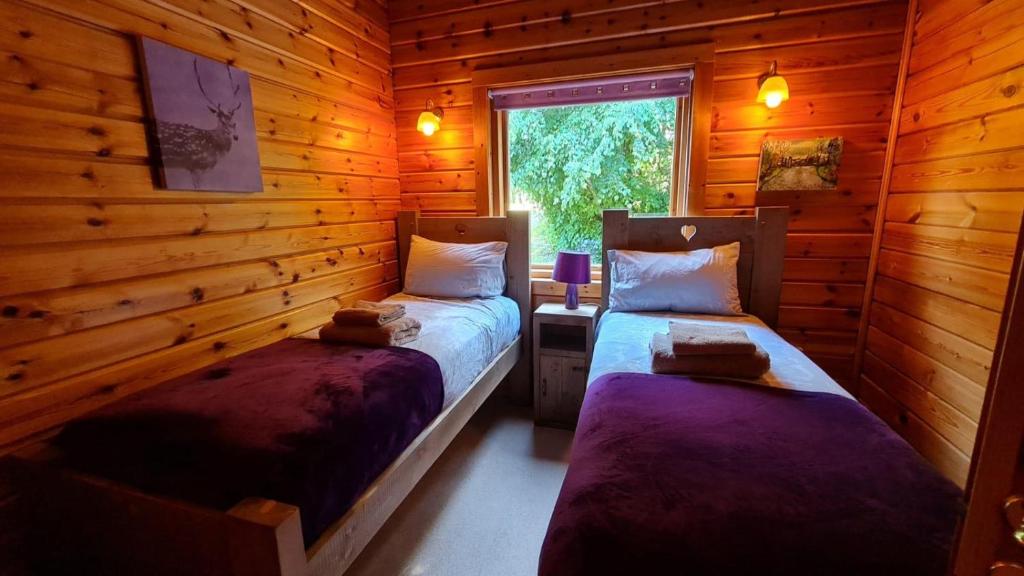 ein Schlafzimmer mit zwei Betten in einer Blockhütte in der Unterkunft Bramble Bank Gisburn Forest Lodge in Skipton
