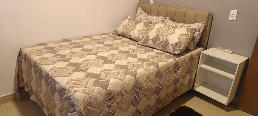 a bed in a bedroom with a nightstand next to it at Casa com piscina in Maceió