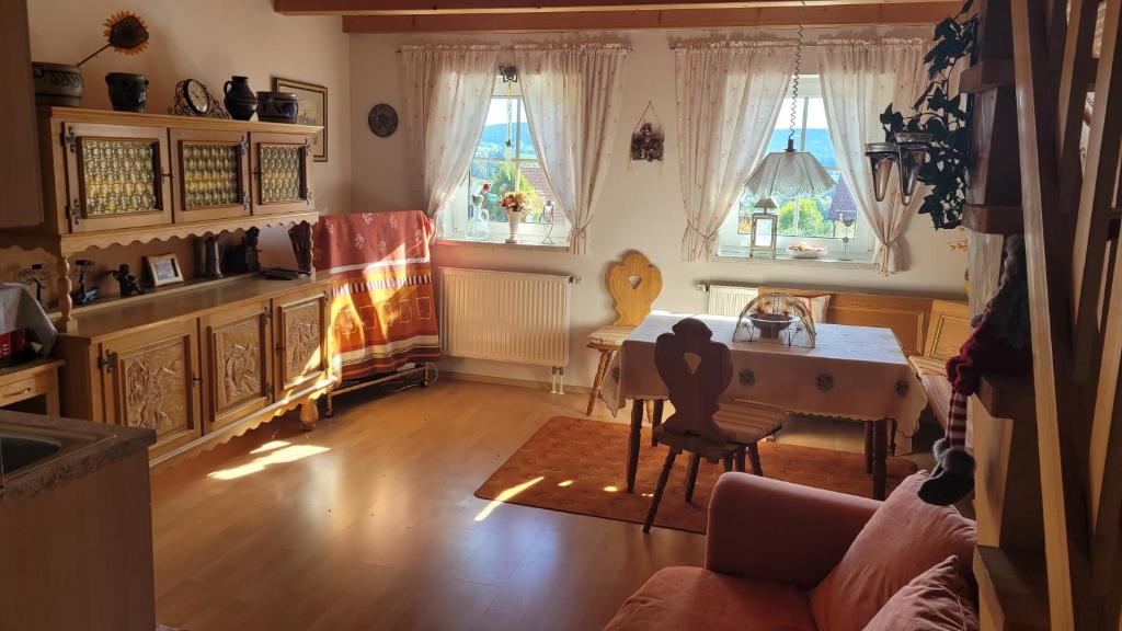 un soggiorno con tavolo e 2 finestre di Ferienwohnung Gerda Riederer a Neualbenreuth