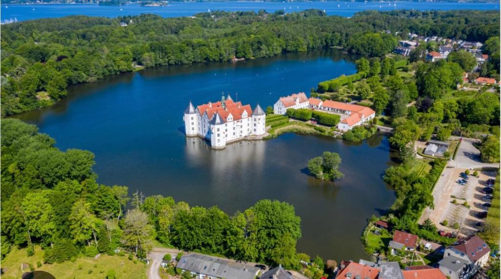 an island in the middle of a lake with a castle at Ferienwohnung am Schlosspark in Glücksburg