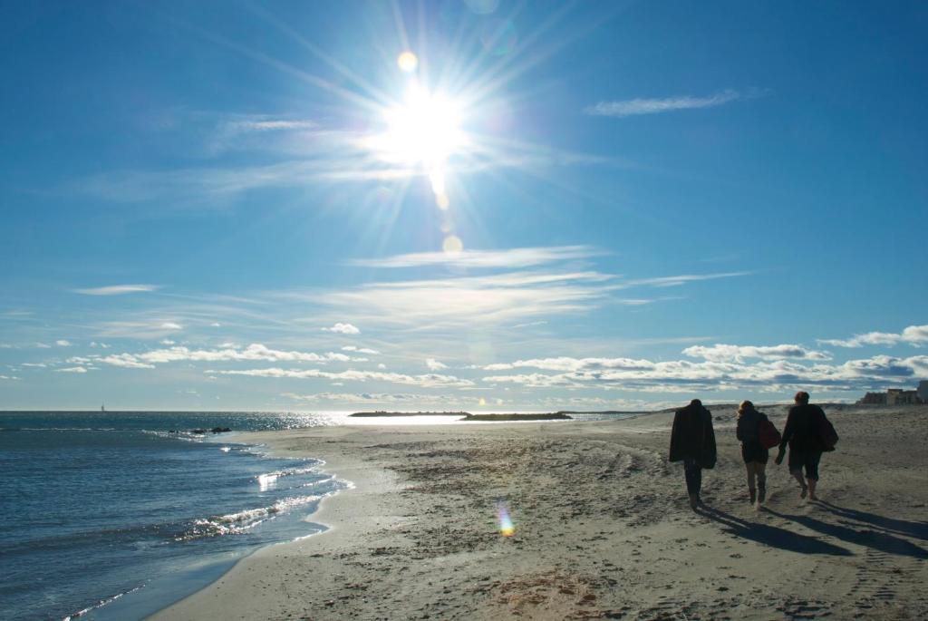 un grupo de personas caminando por la playa en HoteI de la Plage Montpellier Sud, en Palavas-les-Flots