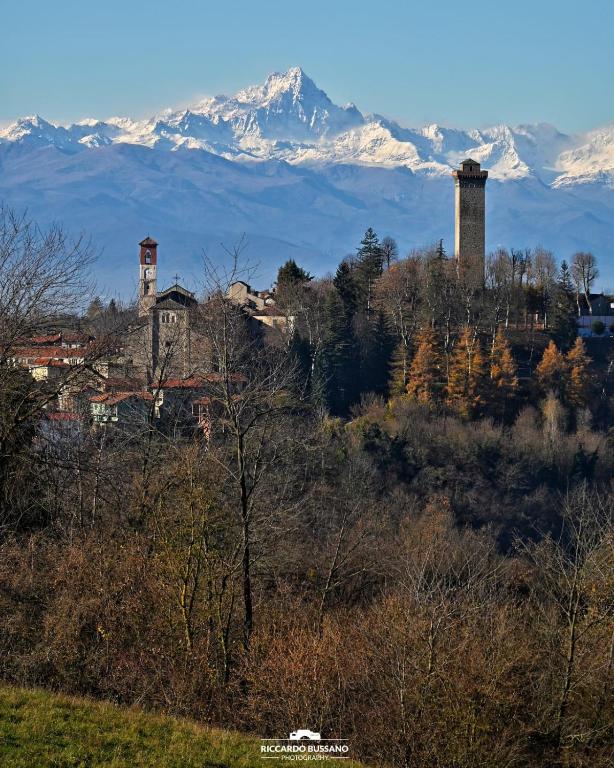 a mountain in the distance with a town and a building and trees at CASCINA BINELLO appartamenti A & B in Belvedere Langhe