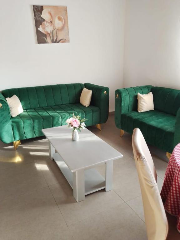 a living room with two green couches and a coffee table at Résidesnce Merveilles M18 in Kribi
