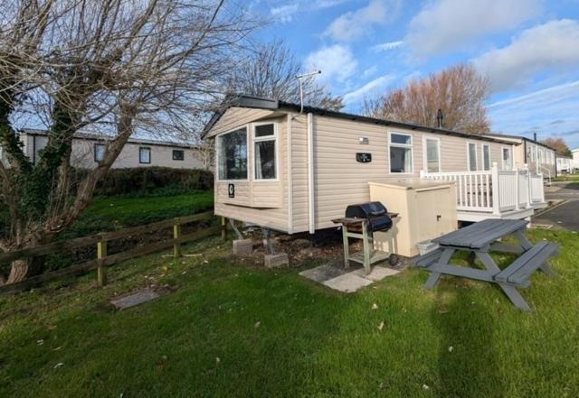 a white tiny house with a picnic table and a bench at Swift Loire Holiday Home sleeps 6 Haven Littlesea in Weymouth