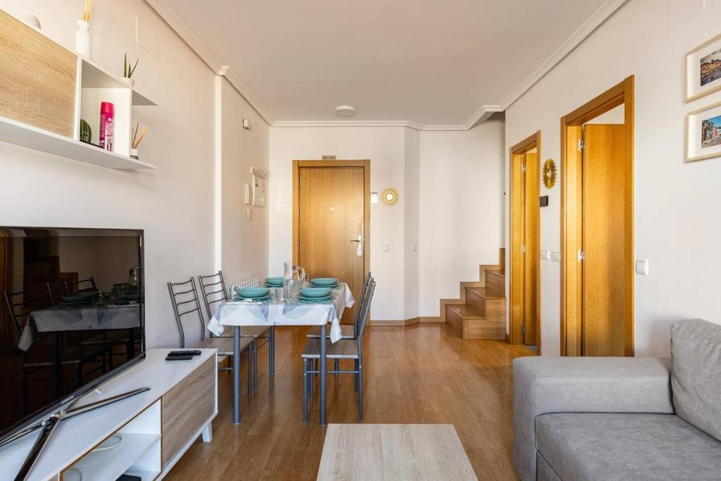 eine Küche und ein Wohnzimmer mit einem Tisch und einer Couch in der Unterkunft apartamento familiar con piscina licencia 14721 in Camarma de Esteruelas