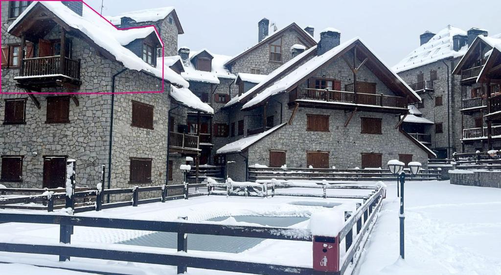 a snow covered building with a pool in front of it at El rincón de Benás in Anciles
