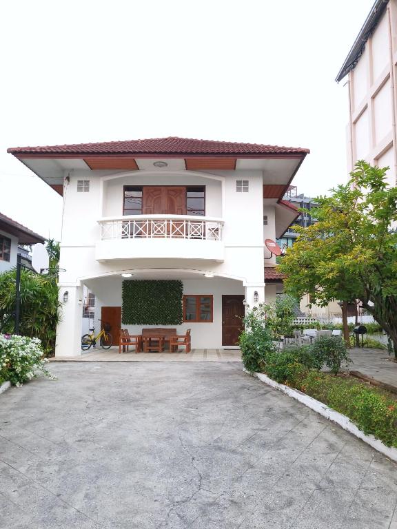 a white house with a balcony and a driveway at Poon house Nimman in Chiang Mai