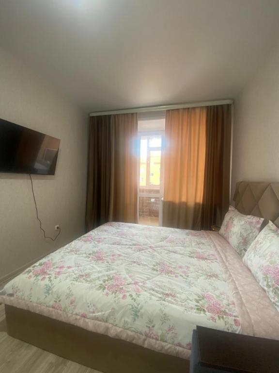 a bedroom with a large bed and a television at Комфортабельные - уютные апартаменты в Костанай Береке 63 in Kostanay