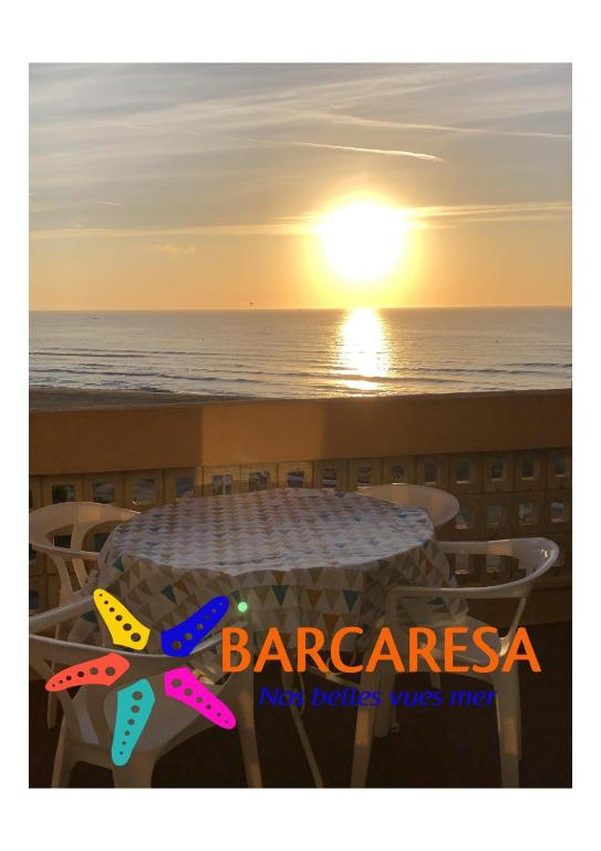- un coucher de soleil sur la plage avec une table et des chaises dans l'établissement Barcaresa-RAVISSANT APPARTEMENT PISCINE VUE MER WIFI PARKING GRATUIT, au Barcarès