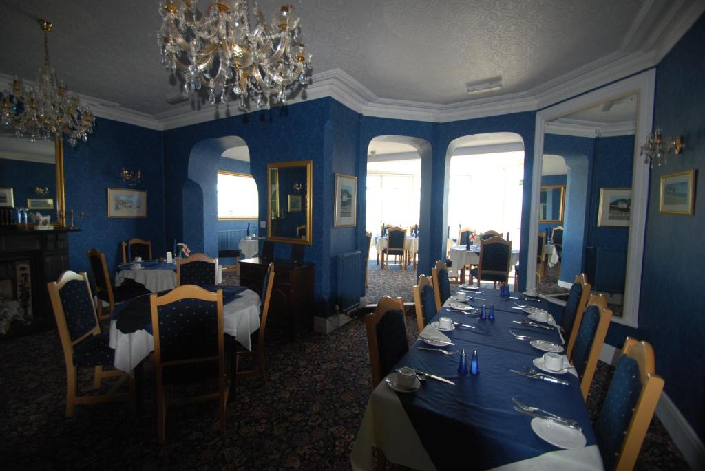 a dining room with blue walls and tables and chairs at Headlands Hotel in Llandudno
