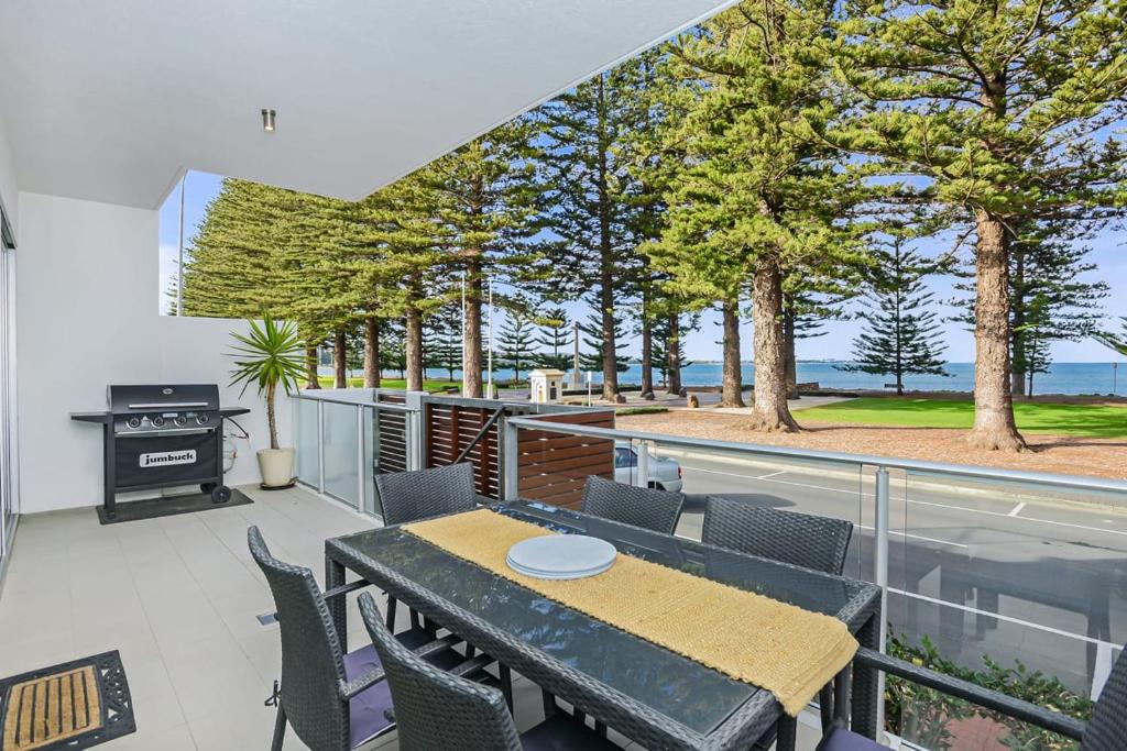 Un patio con mesa y sillas y parrilla. en Luxury beachfront apartment at The Breeze - Free Wifi, en Victor Harbor