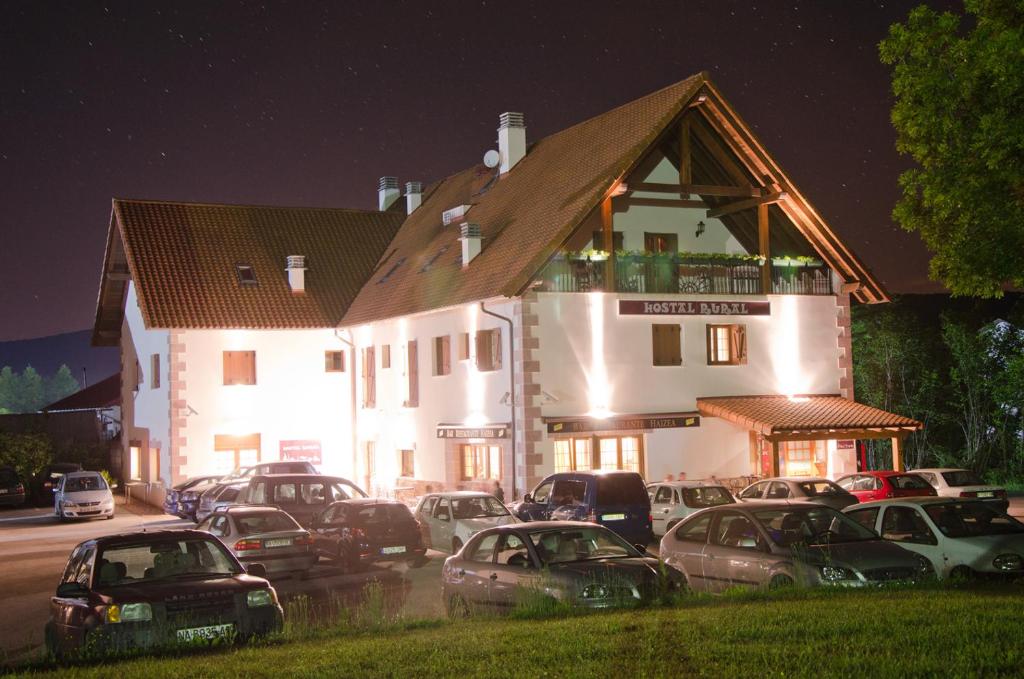 un grande edificio bianco con macchine parcheggiate di fronte di Hostal Rural Haizea a Espinal-Auzperri