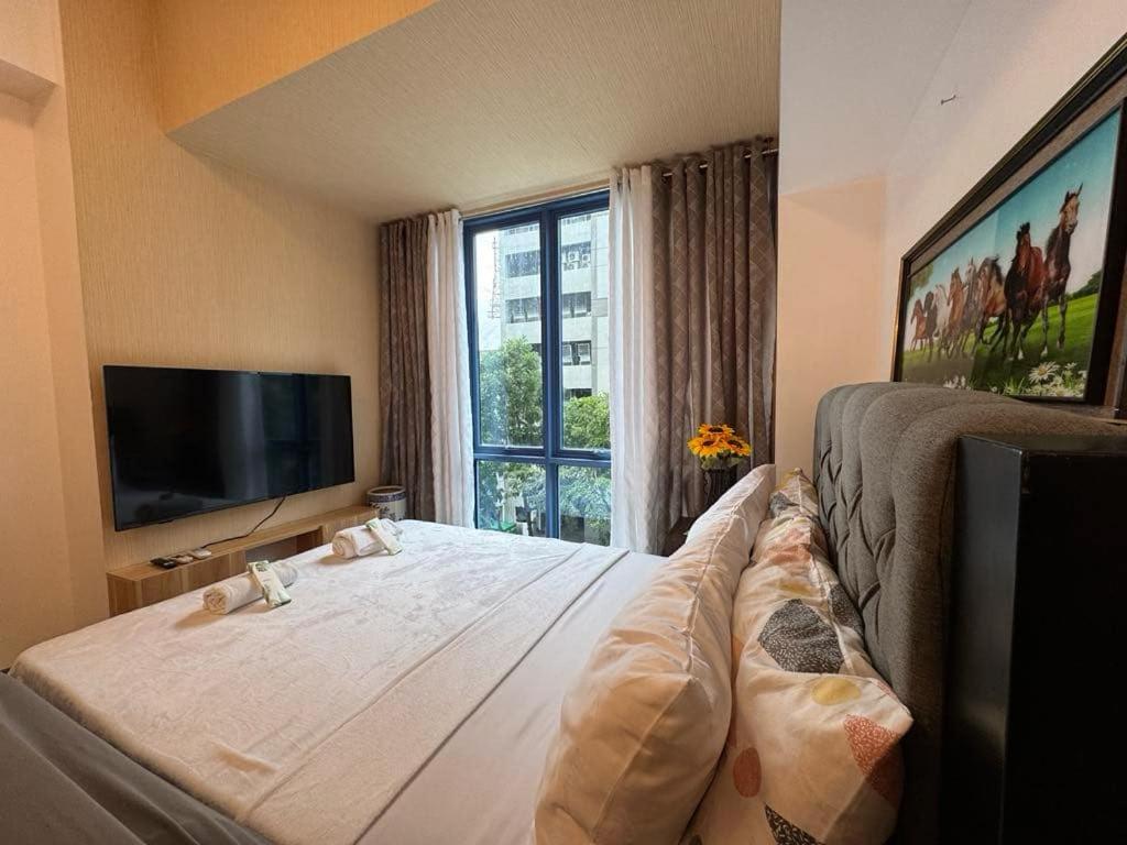 Un dormitorio con una cama grande con una ventana grande. en ARC Studio Unit at 38th Park, en Cebú