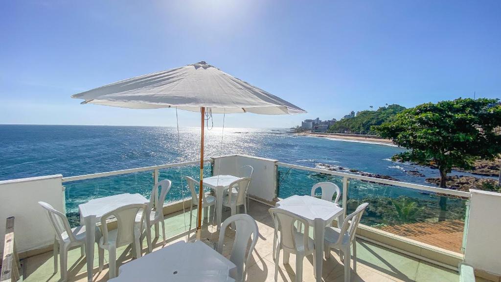 a balcony with tables and an umbrella and the ocean at Hostel Cantinho do Mar in Salvador