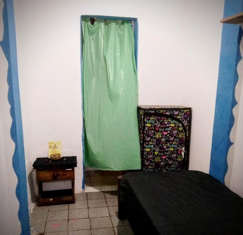 Un dormitorio con una cama y una cortina verde. en Cantinho Esotérico Santo Antônio Salvador, en Salvador