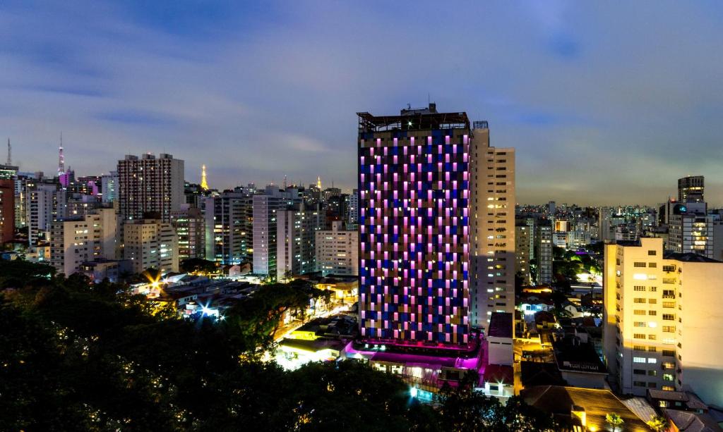 un bâtiment éclairé dans une ville la nuit dans l'établissement Hotel WZ Jardins, à São Paulo