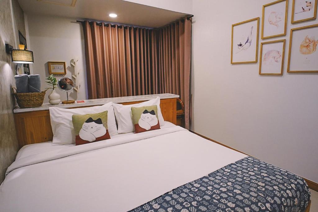 a bedroom with a bed with four cats pillows at Sleepy House Chiang Rai in Chiang Rai