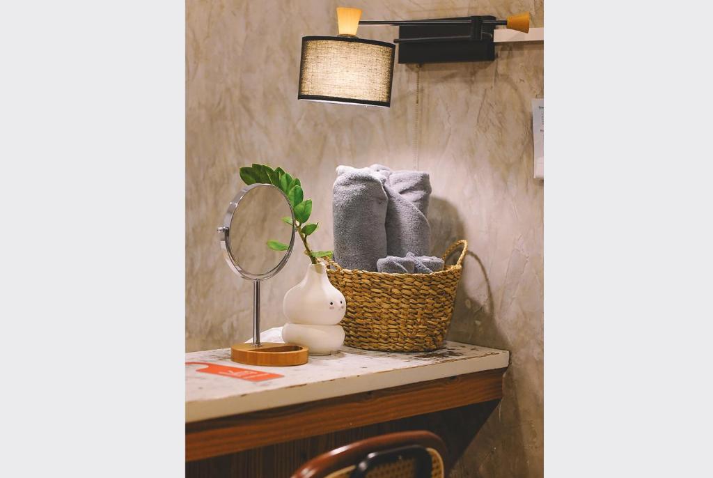 a bathroom counter with a basket of towels and a mirror at Sleepy House Chiang Rai in Chiang Rai