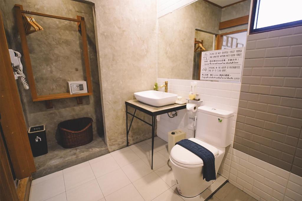 a bathroom with a white toilet and a sink at Sleepy House Chiang Rai in Chiang Rai