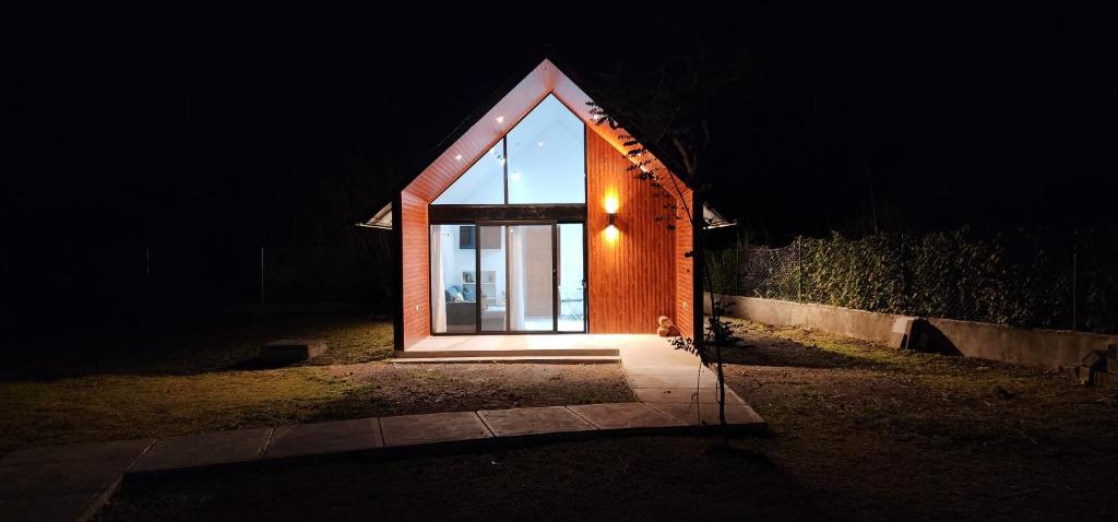 uma pequena casa com uma grande janela na escuridão em Volcano View Cottage em Volcán