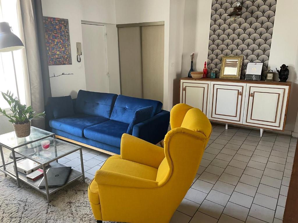 un salon avec un canapé bleu et un fauteuil jaune dans l'établissement Orléans Le charme de l'ancien en hyper centre, à Orléans