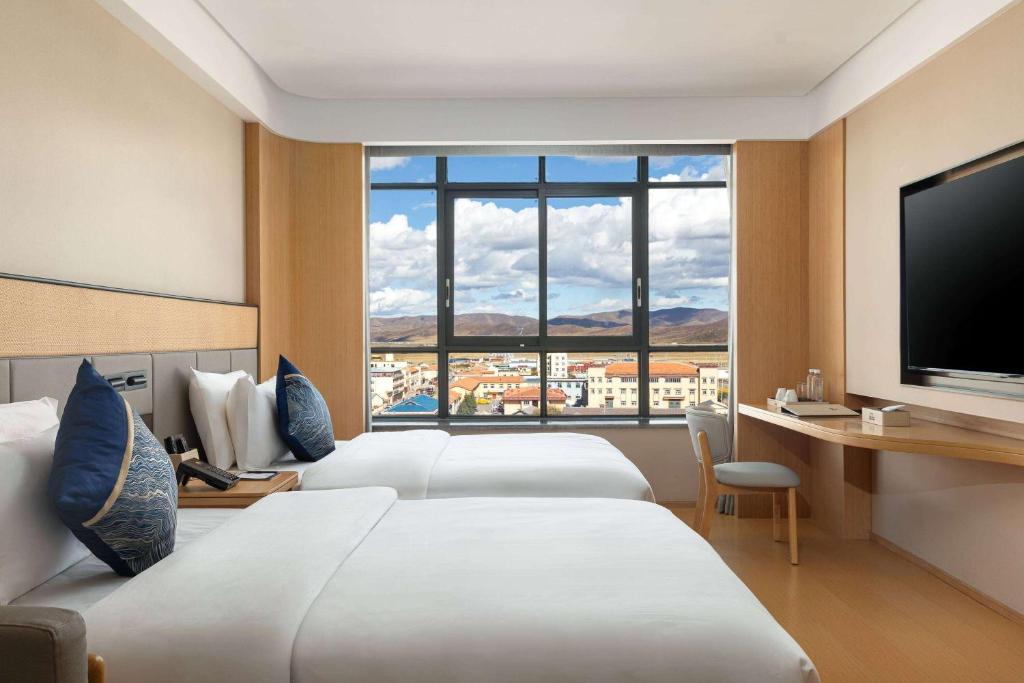 Una habitación de hotel con dos camas y una gran ventana. en Days Hotel by Wyndham Aba Hongyuan, en Hongyuan