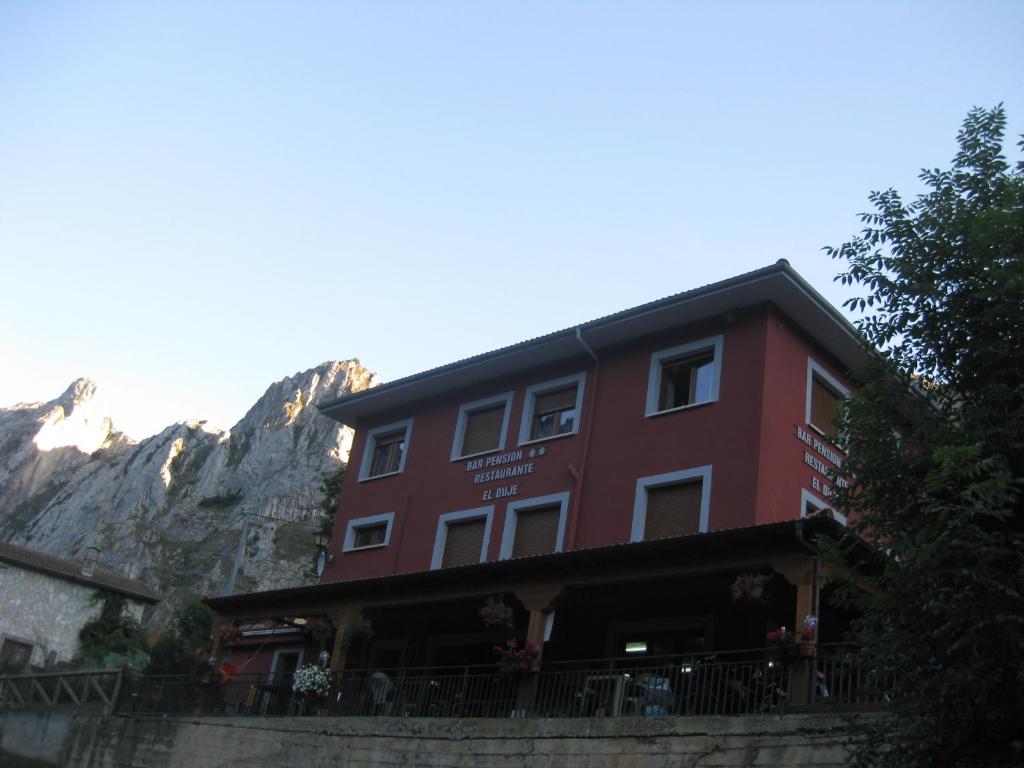 a red building with a mountain in the background at Hostal el Duje in Tielve